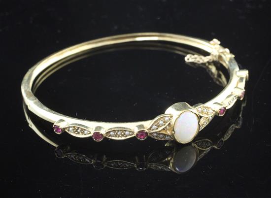 A 1990s Victorian style 9ct gold, white opal ruby and seed pearl set hinged bangle,